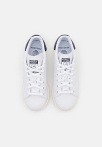 Weiße Leder-Sneaker mit runder Spitze, Schnürung vorne, navy-farbener Ferseinsatz, perforierten Details und tanfarbener Gummisohle. "Stan Smith"-Branding auf der Zunge.