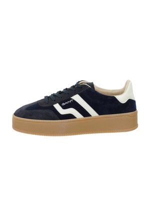 Granatowy zamszowy sneaker z białymi skórzanymi akcentami, czarnymi sznurowadłami i jasnobrązową gumową podeszwą widziany z boku.