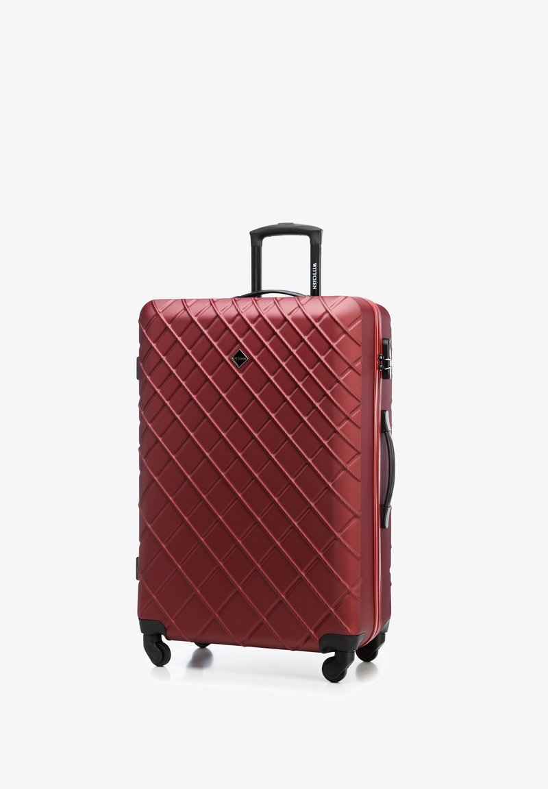 Valigia rigida rossa con texture a motivo diamante, due ruote nere, manico estensibile e una maniglia superiore per un facile trasporto.