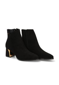 Botas de tobillo de ante negro con punta afilada y cremallera lateral. El tacón grueso con detalles en oro añade contraste a la textura suave.