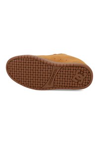 Sålen av en brun DC-sko med teksturert grepmønster, DC-logo og "DCSHOECOUSA"-tekst synlig på gummibunnen.