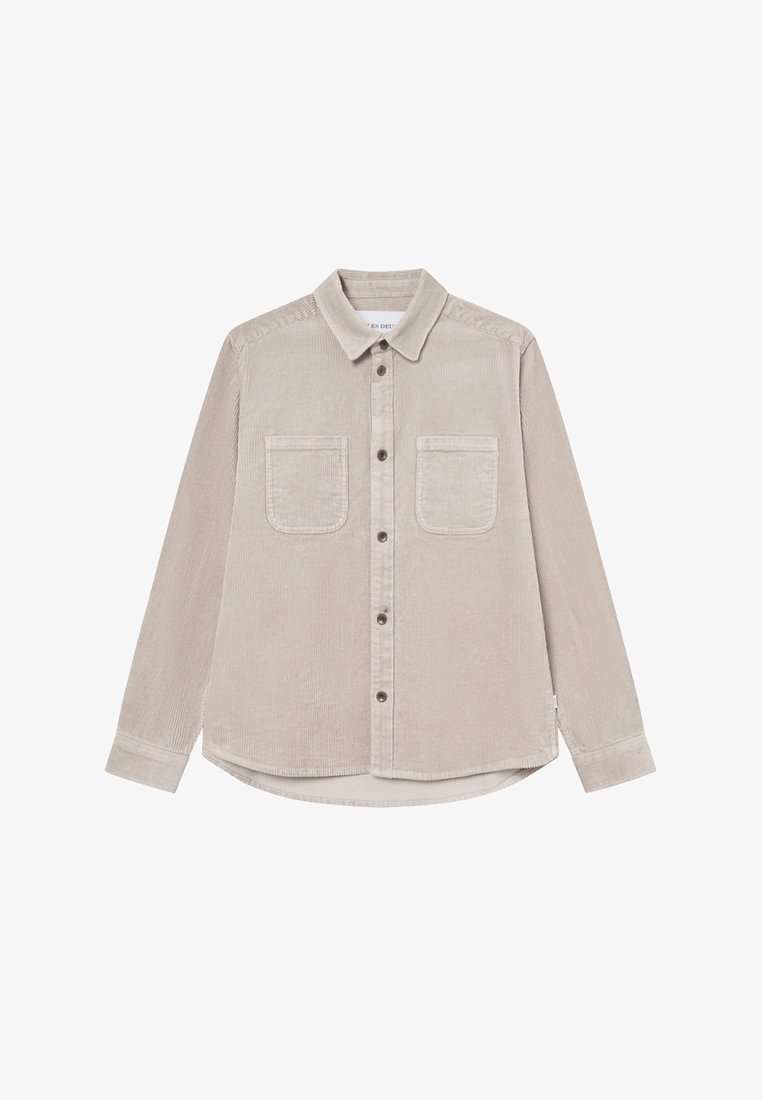 Beige kordflorskjorta med långa ärmar, krage, två bröstfickor och rundad nederkant. Knappstängning och texturerad tyg.