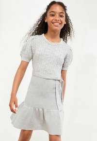 Harmaa neulottu mekko, jossa on lyhyet puff-hihat, ribbattu pinta, helmineckline ja levenevä helma vyötärösolmu yksityiskohdalla.