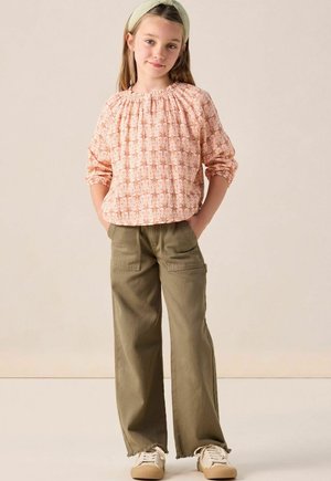 Long-sleeve, gathered-neck blouse in peach with white floral pattern, paired with olive green wide-leg cargo pants and beige sneakers.