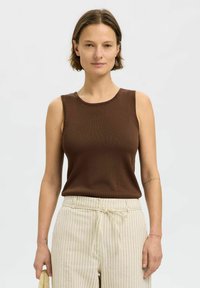 Brun ribbad linne med rund halslinning och ärmlös design, tillsammans med gräddfärgade randiga byxor med elastisk midja.