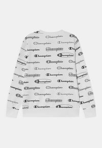 Sudadera blanca con un diseño de logotipos "Champion" en negro repetidos. Puños y bajo acanalados, tela suave, estilo casual de cuello redondo.