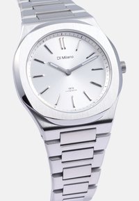 Reloj de acero inoxidable plateado con un dial liso, marcadores minimalistas y una pulsera texturizada con un acabado pulido.