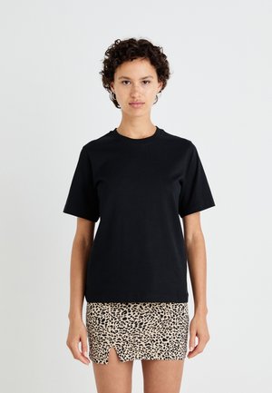 Svart bomulls T-skjorte med korte ermer og rund hals; kombinert med en beige leopardmønstret mini-skjørt med en frontsplitt.