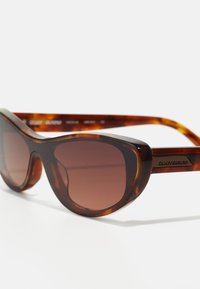 Gafas de sol de carey con un marco geométrico audaz; lentes tintados y acabado suave; logo grabado en la patilla.