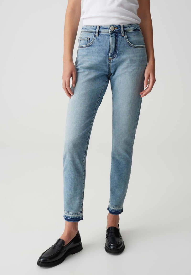 Lichtblauwe denim jeans met een hoge taille, slim fit, vijf zakken en opgerolde boorden, gecombineerd met zwarte instappers.
