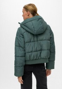 Zelena puffer jakna s kapuljačom, koja ima prošivenu površinu i rebrasti donji rub. Stražnji dio prikazuje skraćenu dužinu i glatku teksturu.