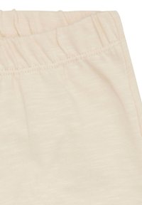 Lichtbeige katoenen broek met een elastische tailleband met plooien en een zachte, gestructureerde stof. De nadruk ligt op eenvoud en comfort in het ontwerp.