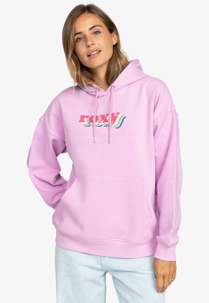Svetlo ružová mikina s predným vreckom, kapucňou na šnúrku a farebnou grafikou "ROXY" v retro písmene. Mäkkučký materiál a pohodlný strih.