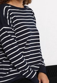 Navyblau-weiß gestreifter Pullover mit Rundhalsausschnitt, langen Ärmeln und gerippten Bündchen. Aus weichem Stoff gefertigt, mit einem lässigen Schnitt.