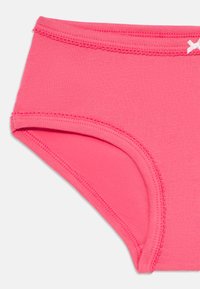 Helle pinke Baumwoll-Mädchenunterhosen mit elastischem Bund, gewelltem Stich und kleinem weißen Schleifchen oben rechts.
