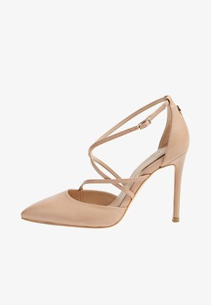 Nude leather high-heeled shoe with a pointed toe, ankle strap, and crisscross design. Features a slender stiletto heel and smooth texture.