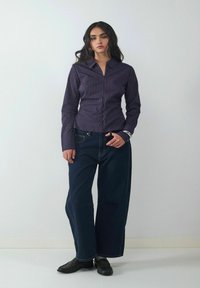 Navy gestreiftes Hemd mit Knopfleiste, Kragen und langen Ärmeln, kombiniert mit dunkelblauen, weiten Jeans und schwarzen Mokassins. Schlichtes, tailliertes Design.