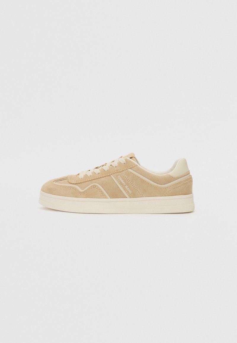 Sneaker in suede beige con design a collo basso, caratterizzata da accenti color crema e una suola testurizzata. Dettagli di cucitura sottili e logo sul lato.
