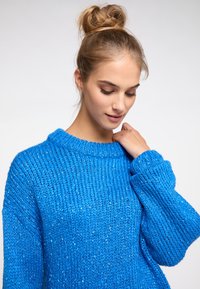 Blue knitted sweater with a round neckline, chunky texture, and loose fit. Features long sleeves and a slightly oversized design.