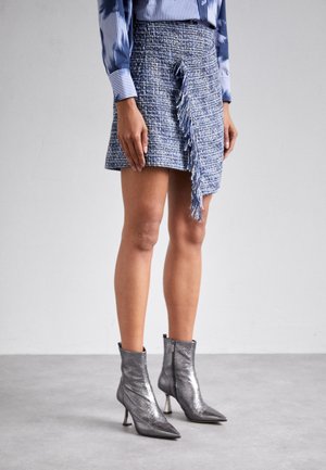 Blue tweed skirt with fringed detail at the front, paired with shiny silver ankle boots featuring a pointed toe and stiletto heels.