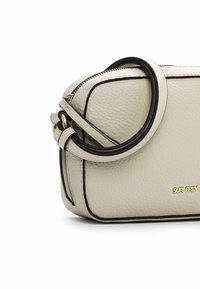 Borsa a tracolla in pelle crema con bordi neri, accessori in oro e zip superiore. Presenta un design arrotondato e una tracolla regolabile.