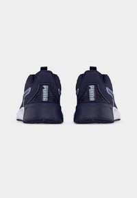 Ζεύγος σκούρων μπλε αθλητικών παπουτσιών Puma, εμφανιζόμενα από πίσω, με λευκές ενδιάμεσες σόλες και το λογότυπο Puma στις ταμπέλες της φτέρνας, σε λευκό φόντο.