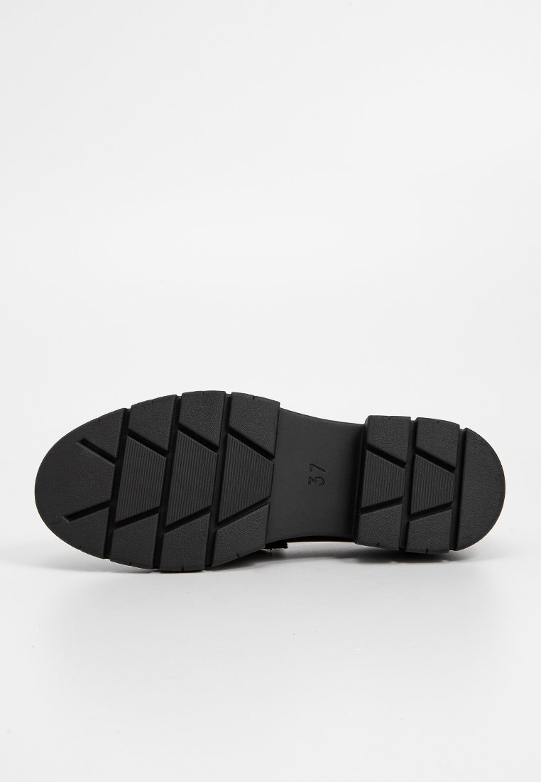 Sole in gomma nera con superficie testurizzata e patterned, e un design del battistrada pronunciato. Contrassegnato con la taglia 37 per identificazione.