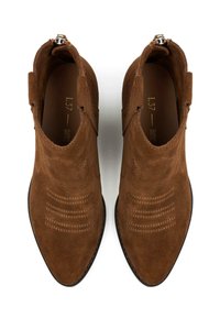 Stivaletti in suede marrone con cuciture decorative, punte arrotondate e zip laterali, mostrati da una vista dall'alto su uno sfondo bianco.