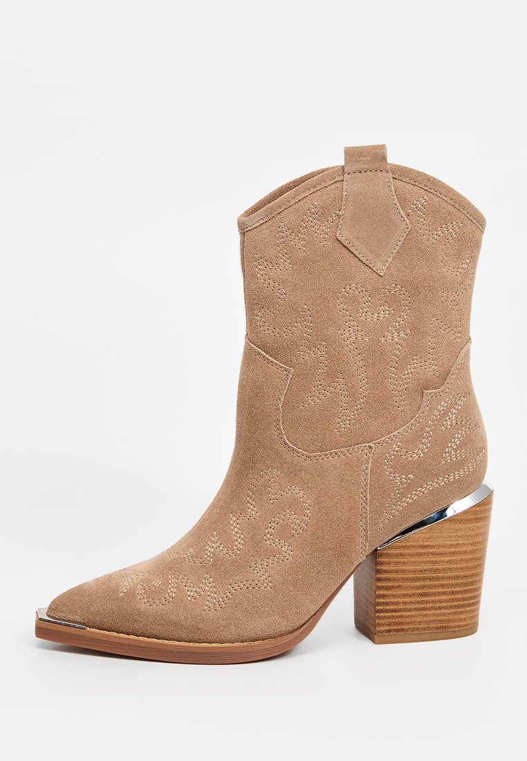 Bota cowboy de ante marrón con punta afilada, costuras decorativas y un tacón de bloque de madera con un acento cromado.