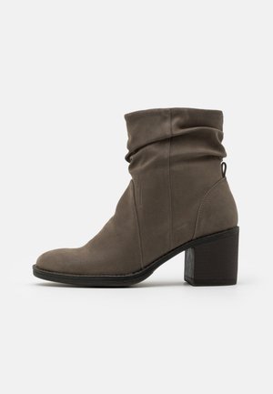 Enkellaars in taupekleurig suède met een slappe schacht, een ronde neus, een zwart blokhakje en een aantreklipje aan de achterkant.