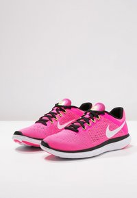 Scarpe sportive rosa con tomaia in rete, dettagli neri, logo Nike bianco e lacci verdi. Presentano una suola ammortizzata per il massimo comfort.