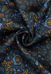 Donkere stof met blauwe, gele en bruine bloemenpatronen, gevouwen en gedraaid om de textuur en ingewikkelde ontwerpelementen te tonen.
