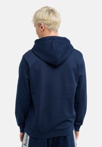 Marineblaues Hoodie aus weichem Stoff, mit Kordelzugkapuze, gerippten Bündchen und lockerer Passform. Rückseite zeigt keine Grafiken.