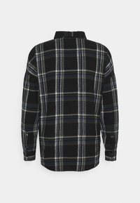 Svart rutig skjorta med blå och gula linjer. Långa ärmar, krage och avslappnad passform. Mjuk tyg med en strukturerad mönster.