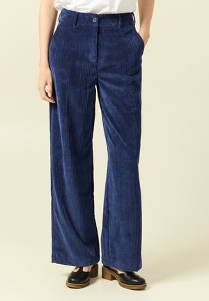 Mörkblå kordfläta byxor med vida ben, framfickor och knappstängning. Texturerat tyg med vertikala räfflor.