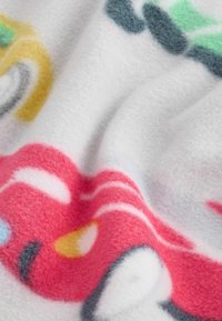 Plyšová deka s bílým pozadím a barevnými abstraktními vzory v růžové, žluté, zelené a modré. Měkká textura, útulný vzhled.