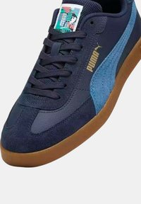 Zapatillas con paneles de ante y cuero en azul marino y azul claro, suela de goma, cordones texturizados y una etiqueta tejida en la lengüeta.