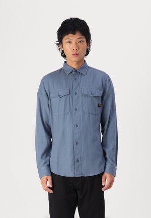 Blaues langärmeliges Hemd aus leichtem Stoff, mit Button-Down-Kragen, zwei Brusttaschen und einem schlanken Design.