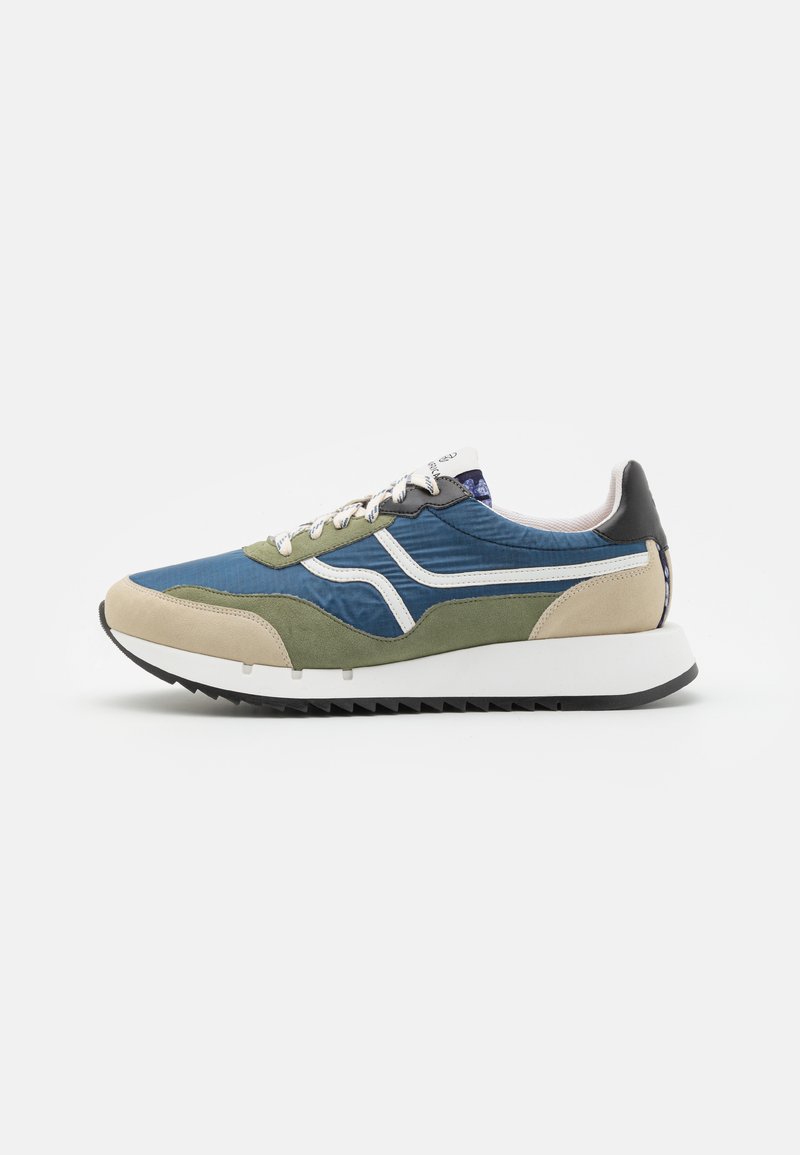 Sneakers with a blue upper, green suede accents, beige toe cap, white stripes, and a black heel. Textured materials with a rubber sole.