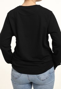 Black sweatshirt with long sleeves, a round neckline, and ribbed hem. Pair of blue jeans with a fitted design. Solid color, no patterns.