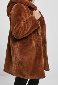 Brun faux fur frakke med hætte, i en blød, pelsagtig tekstur og en afslappet pasform, designet med åben front og lange ærmer.