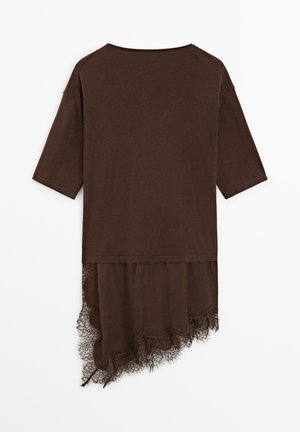 Brun kortærmet top med asymmetrisk kant, der har blonder, som er længere på den ene side.