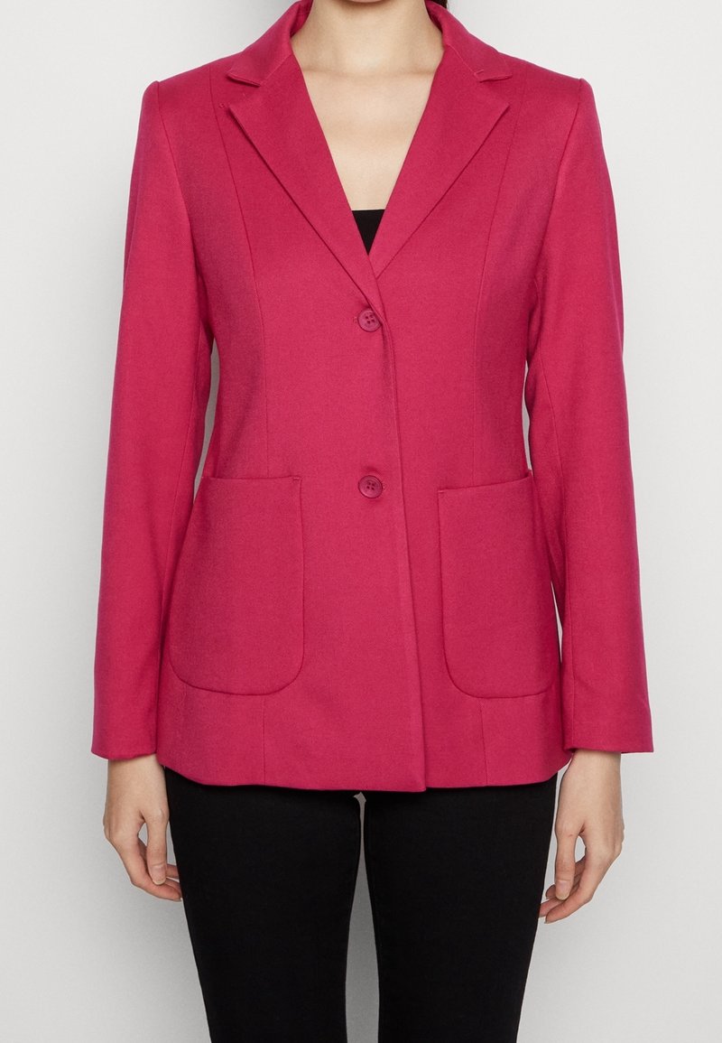 Blazer fucsia con colletto a punte, due tasche frontali e chiusura a due bottoni; presenta una vestibilità sartoriale e un tessuto testurizzato.