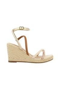 Sandalia de cuña beige con suela de yute trenzado, tiras metálicas, hebilla ajustable en el tobillo y diseño de punta abierta. Textura suave, forma elegante.
