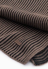 Couverture en tricot à rayures brunes et noires avec une finition texturée et une petite étiquette portant le nom "andie" sur le bord.