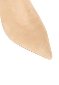 Nude pointed-toe high heel shoe made of suede, featuring a smooth texture and tapered silhouette for a sleek design.