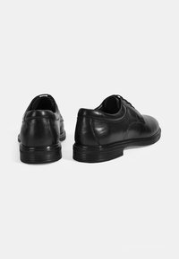 Zwarte leren dresschoenen met een gladde afwerking, ronde neus en een lage rubberen zool. Voorzien van veters en subtiele stiksels.