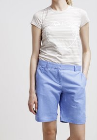 T-shirt à manches courtes rayé blanc avec un logo circulaire, associé à un short en coton bleu clair avec poches latérales et une coupe décontractée.