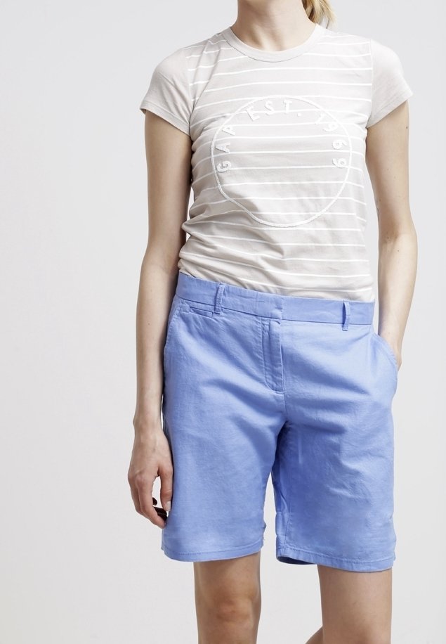 T-shirt à manches courtes rayé blanc avec un logo circulaire, associé à un short en coton bleu clair avec poches latérales et une coupe décontractée.