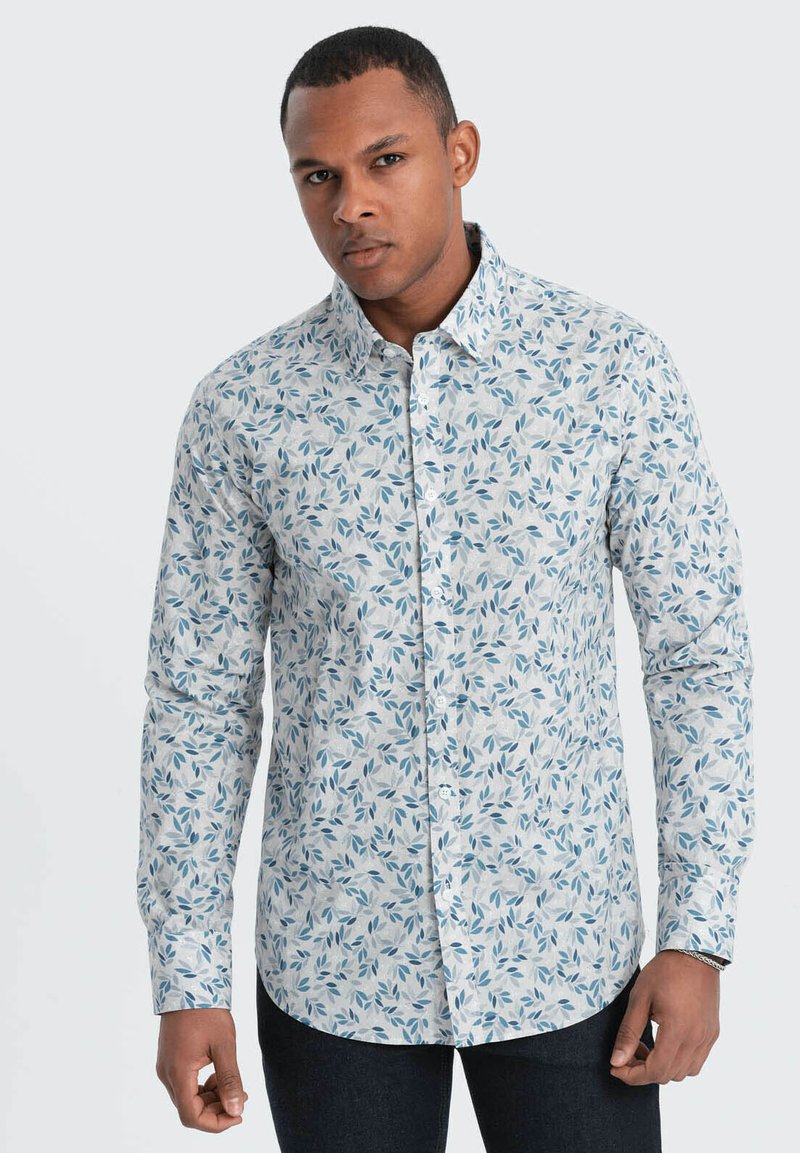 Lange mouw overhemd van lichte stof met een witte basis, voorzien van een blauw loofpatroon, knoopsluiting bij de kraag en manchet mouwen.